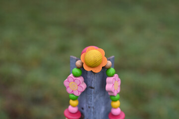 Naklejka premium buntes rosa orange schnullerband mit holzperlen über holzpfosten