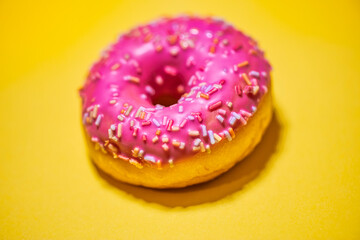 Homemade circle donut with pink icing and rainbow sprinkles