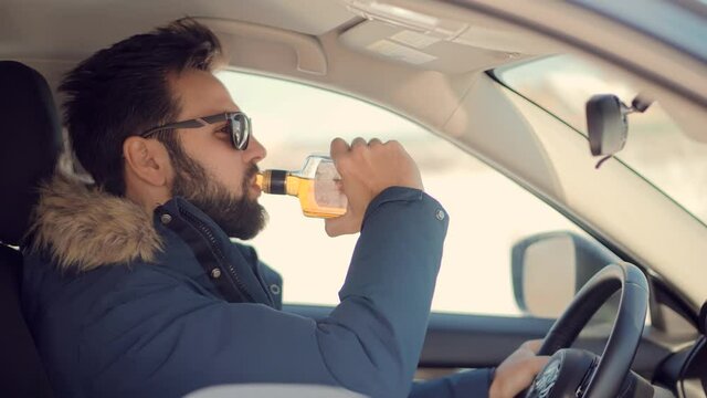 Drunk Driver Sitting On Car.Tired Man Illegal Vehicle Driving.Drunken Drive Risk Car Accident.Man Holding Alcohol Bottle In Car. Dangerous On Road Drunk Driving. Stress Unlawful Intoxicated Drive Auto