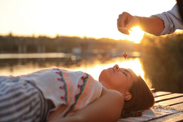 Woman at crystal healing session near river outdoors
