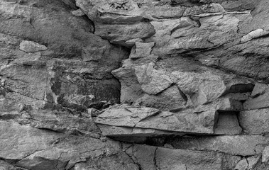 Grungy stone rocky slate facade of worn mining quarry. Uneven strong caving chipped granite slices of shabby boulder edge blocks. Rustic hewn bumpy grunge of vintage big bold cliff for 3D rough design