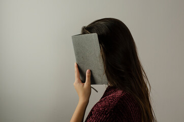 woman covering her face with a notebook
