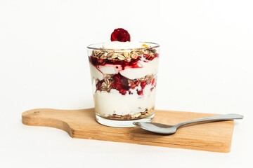 Muesli with raspberries and yogurt in a glass with a spoon.