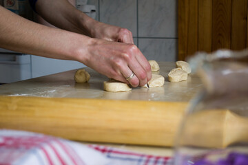 Close up of female hands preparing raw unbaked dough on table in small domestic kitchen