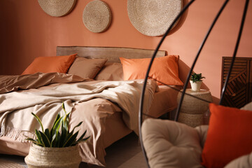 Bed with orange and brown linens in stylish room interior