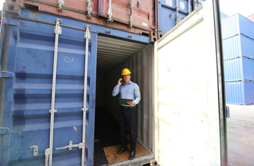 Naklejka na ściany i meble Engineer or supervisor checking and control loading Containers box from Cargo at harbor.Foreman control Industrial Container Cargo freight ship at industry.Transportation and logistic concept.