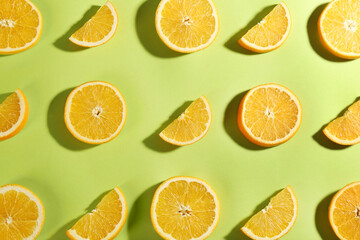 Slices of delicious oranges on green background, flat lay