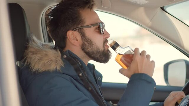 Drunk Driver Sitting On Car.Tired Man Illegal Vehicle Driving.Drunken Drive Risk Car Accident.Man Holding Alcohol Bottle In Car. Dangerous On Road Drunk Driving. Stress Unlawful Intoxicated Drive Auto