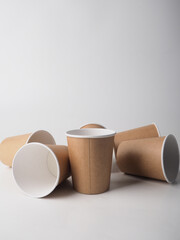 Several paper disposable brown cups are randomly placed on a white background