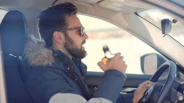 Drunk Driver Sitting On Car.Tired Man Illegal Vehicle Driving.Drunken Drive Risk Car Accident.Man Holding Alcohol Bottle In Car. Dangerous On Road Drunk Driving. Stress Unlawful Intoxicated Drive Auto