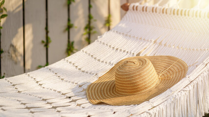Fototapeta na wymiar Close up straw hat laying on white hammock outdoor. Relaxing summer vacation concept.
