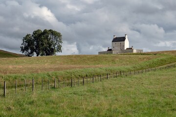 Fototapeta na wymiar Landscape with white Corgarff Castle and a tree in Scottish landscap