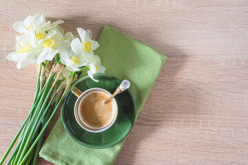 Vintage cup of coffee and bouquet of white daffoidils on empty wooden background. Top view, space for text