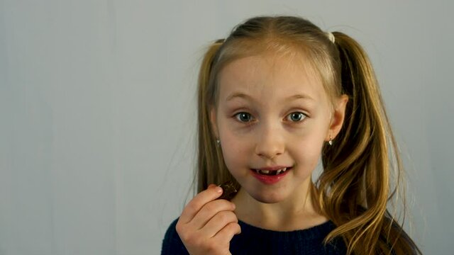 portrait of a little girl isolate on a white background. Girl eating delicious chocolate and smiling