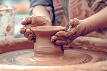 Hands of a potter at work. Potter making ceramic mug on the pottery wheel