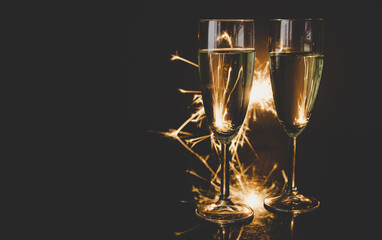 Two glasses of champagne with sparklers in background. New Year's Eve celebration, with copy space.