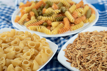 Variety of dry pasta on white plates