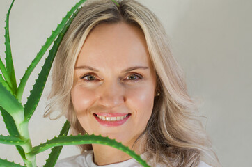 Naklejka premium Women holding a pot with Aloe Vera plant at home. Growing the aloe plant at home. Slow beauty. Skin care with aloe vera. Houseplants care and love, natural cosmetic, home beauty and skinimalism. 