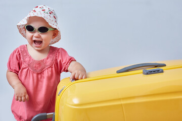 Portrait of a laughing girl with a large suitcase in her hands. Travel and leisure concept with copyspace.