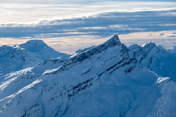 beautiful snow covered mountain peak with cloud lines in the sky at sunset swiss alps