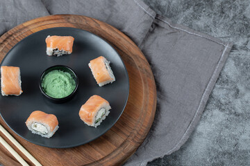 Salmon sushi rolls served with wasabi sauce on a wooden board