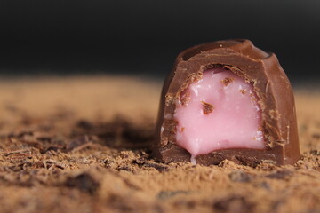 Chocolate's day enclosure chocolate candy with stuffing rests on cocoa on a grey black background...