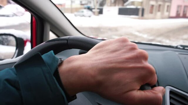 The driver's hand touches the steering wheel while driving a car in the city. Management of vehicles in winter. Compliance with traffic rules.