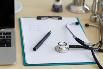 The doctor's desk had a note pad, a notebook, a pen, a stethoscope, a pressure gauge.