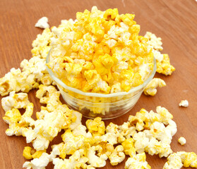 Bowl of fresh popped popcorn isolated on wooden board