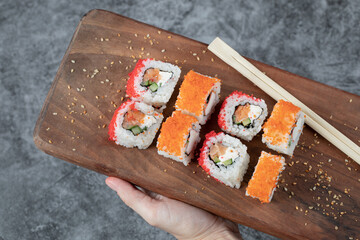 Sushi rolls with yellow and red caviar on a wooden board