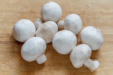 fresh raw champignons on wooden board close up