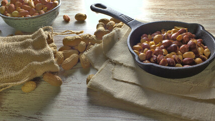 cacahuetes crudos, pelados y fritos, composición fotográfica con cacahuetes fritos en una sartén de hierro fundido
