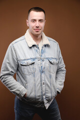 Portrait of an attractive young man in the studio on a brown background. Well-groomed contented smiling nice guy looking at the camera
