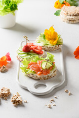 Rice crispbread cake with red fish and vegetables on white background. Festive summer party. Vertical format. Great appetizer.