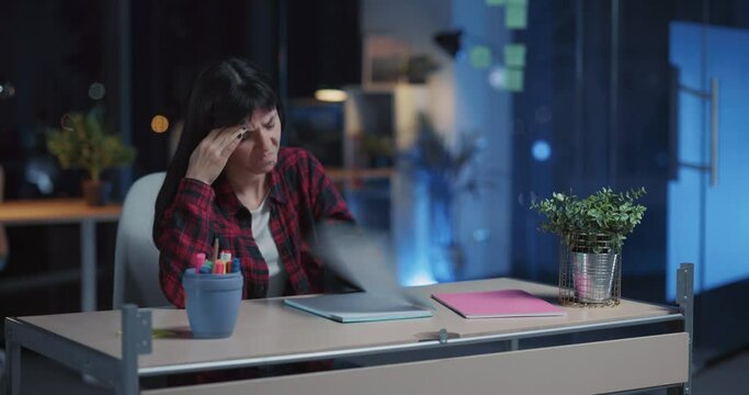 Displeased young caucasian woman working overtime in night office throwing personal things away getting angry. Emotions. Exhaustion from work.