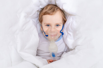 sick baby boy with inhaler treats throat at home, the concept of health and inhalation treatment