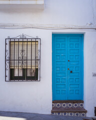 White house facade and blue door in Frigiliana, one of the most beautiful white villages ("pueblo blanco") of Andalucia (Spain)