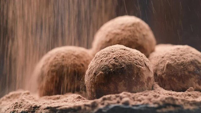 Cocoa powder falling on luxury homemade truffle candies, slow motion of falling chocolate powder on praline bonbon