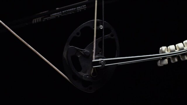 Close up on compound bow mechanisms as string is pulled back