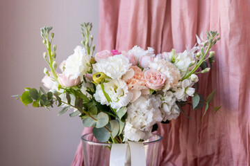 Delicate wedding bouquet in pastel shades from artificial flowers top view close-up in vase on pink fabric background