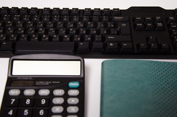 green notepad, calculator, keyboard lie on a white background