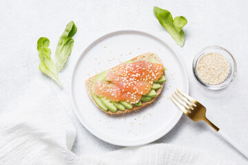 Bran bread toast with salmon and avocado on white stone table background. Flat lay, top view, copy space