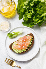 Whole grain rye bread toast with salmon and avocado on white stone table background. Flat lay, top view