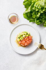 Salmon avocado tartare with sauce on white stone table background. Flat lay, top view, copy space