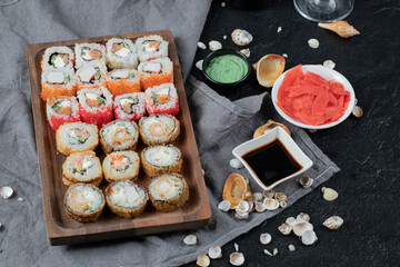 Sushi set on a wooden platter with soy sauce, ginger and wasabi