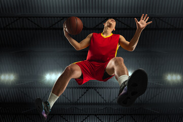 Young professional basketball player in action, motion isolated on black background, look from the...