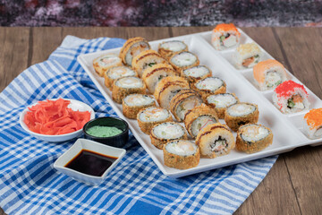Hot fried sushi rolls in a white ceramic platter with ginger, soy sauce and wasabi