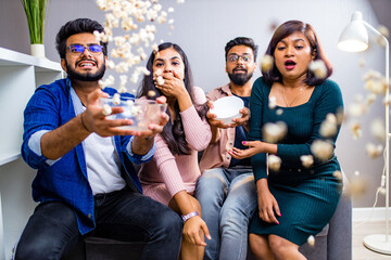 four indian friends watching cinema in the night time at home throwing popcorn