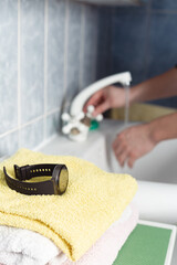Concept of taking off wrist watch before washing hands. Smart device on yellow towel and man's hand...
