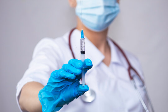 A doctor holds a medical injection syringe and a stethoscope.